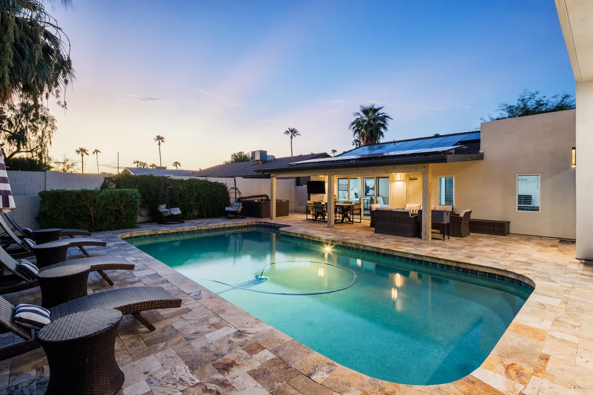 A tranquil outdoor space featuring a sparkling swimming pool, stylish patio seating, and lush landscaping. The inviting area is perfect for relaxation, informal meetings, or socializing after a productive day.