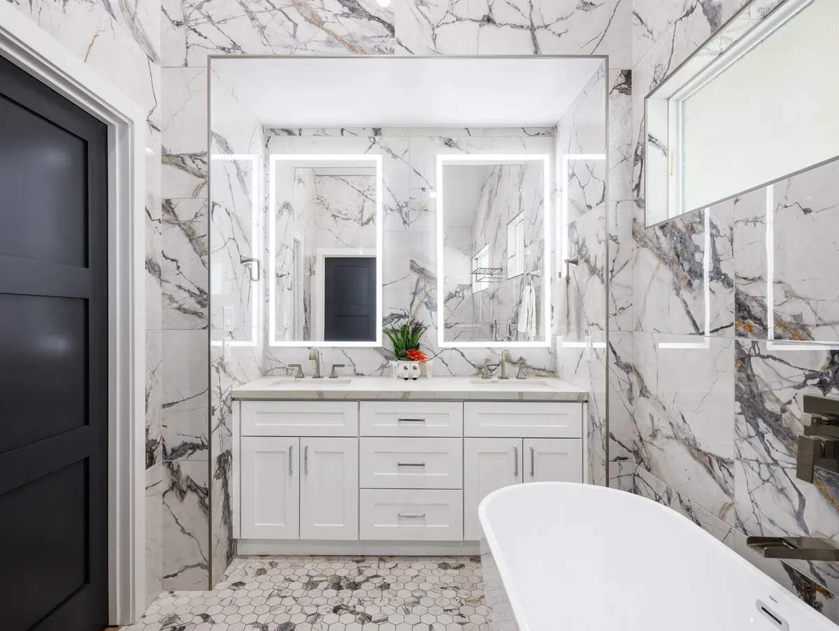 A sophisticated bathroom featuring a luxurious freestanding bathtub, double sinks with LED mirrors, and elegant marble walls. The serene ambiance is perfect for relaxation and self-care, capturing the pampered feeling described in the section.